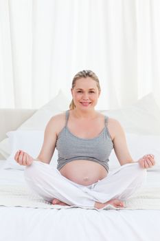 Pregnant woman practicing yoga on her bed