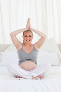 Pregnant woman practicing yoga on her bed