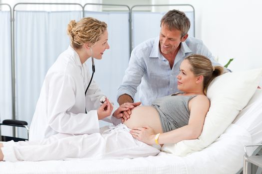 Pregnant woman with her husband listening to the nurse