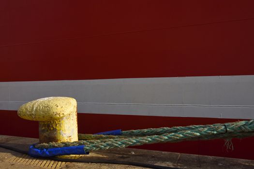 A red ship secured to a pier bollard with mooring lines, Cape Town, South Africa