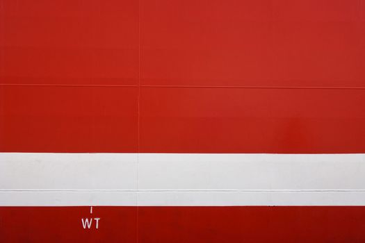 Metal hull of a large red ship with horizontal white weight load line, Cape Town, South Africa