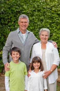 Grandparents with their children looking at the camera in the garden