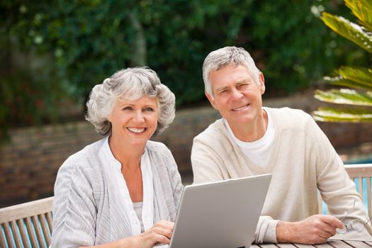 Retired couple working on their laptop outdoors