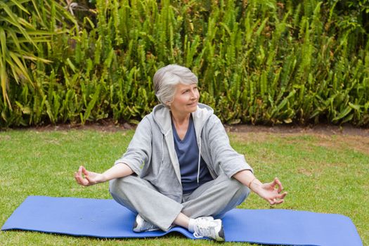 Retired woman practicing yoga in the garden