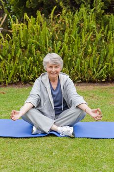 Retired woman practicing yoga in the garden