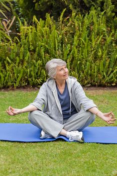 Retired woman practicing yoga in the garden