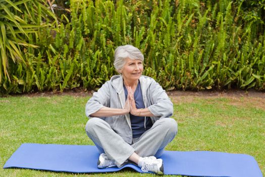 Retired woman practicing yoga in the garden