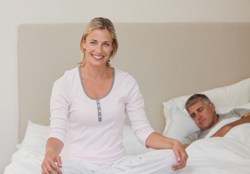 Lovely woman practicing yoga on her bed