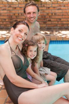 Happy family beside the swimming pool