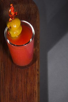 Bloody mary cocktail with olives on a wooden table