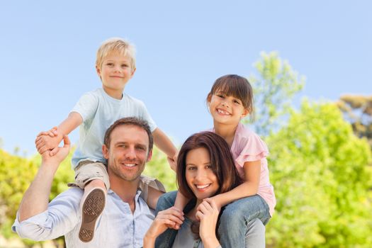 Parents giving children a piggyback in the park