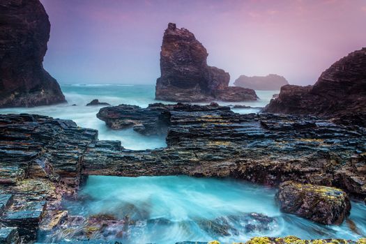 Natural bridge over tidal flows along a craggy coast battered by large waves
