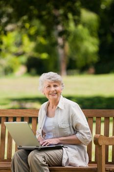 Mature woman working on her laptop on the bench