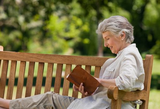 Retired woman reading a book on the bench