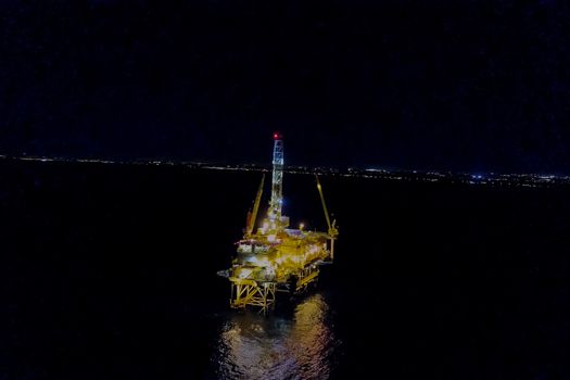 Drilling platform in the port. Oil platform at night in the light of its own lighting. Towing of the oil platform.