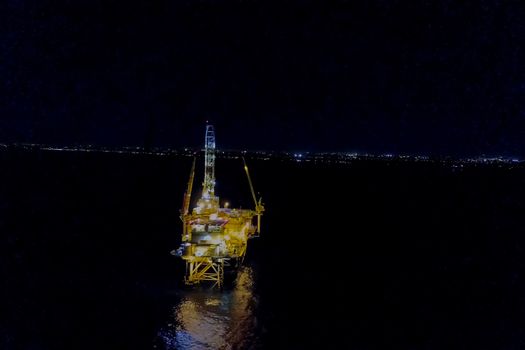 Drilling platform in the port. Oil platform at night in the light of its own lighting. Towing of the oil platform.