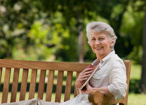 Retired woman reading a book on the bench