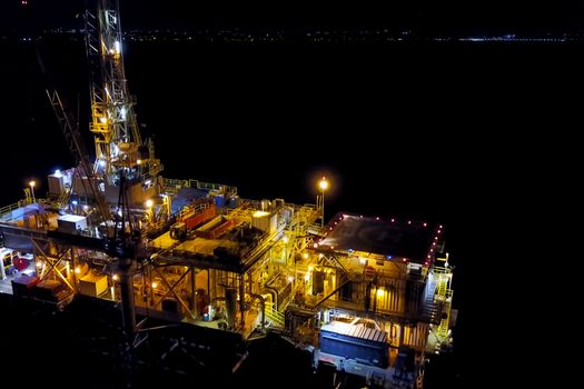 Drilling platform in the port. Oil platform at night in the light of its own lighting. Towing of the oil platform.