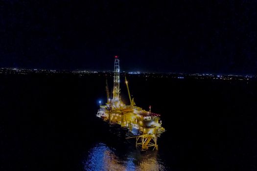 Drilling platform in the port. Oil platform at night in the light of its own lighting. Towing of the oil platform.