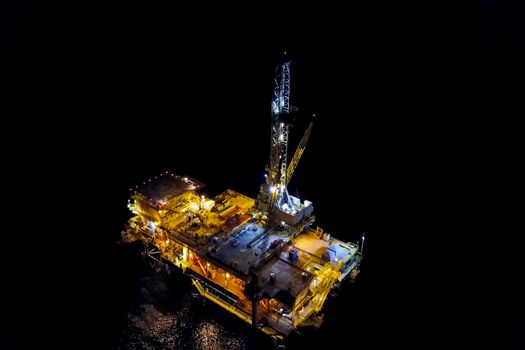 Drilling platform in the port. Oil platform at night in the light of its own lighting. Towing of the oil platform.