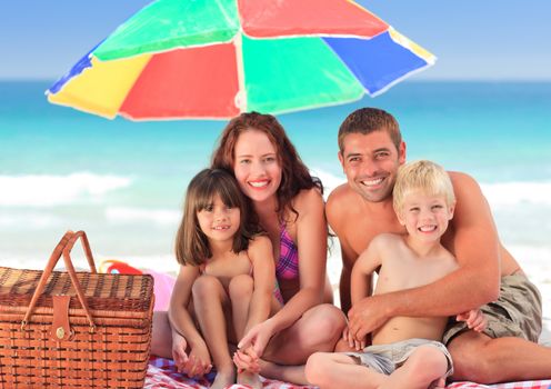 Family posing under a beach umbrella on the beach