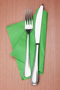 Fork and knife in a green cloth isolated on white