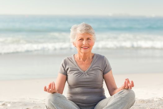 Senior woman practicing yoga on the beach