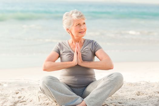 Senior woman practicing yoga on the beach