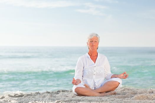 Mature woman practicing yoga on the beach