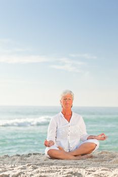 Mature woman practicing yoga on the beach