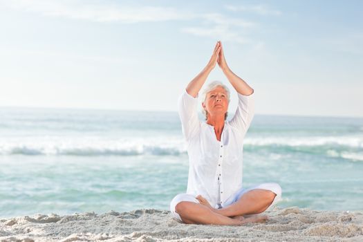 Mature woman practicing yoga on the beach