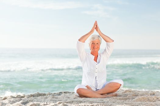 Mature woman practicing yoga on the beach