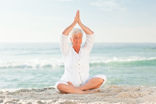 Mature woman practicing yoga on the beach