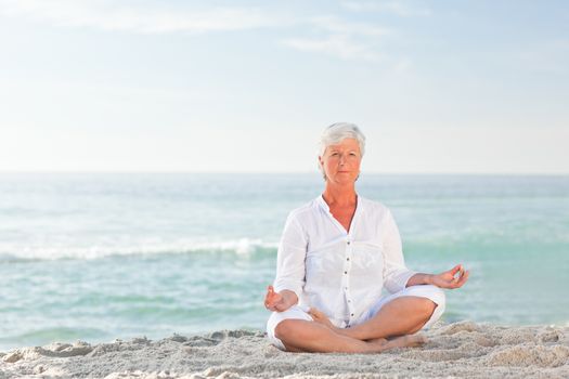 Mature woman practicing yoga on the beach