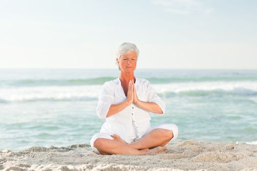 Mature woman practicing yoga on the beach