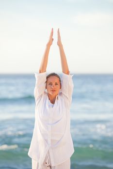 Woman practicing yoga at the beach against the sea