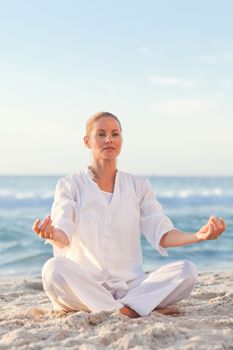 Peaceful woman practicing yoga on the beach against the sea