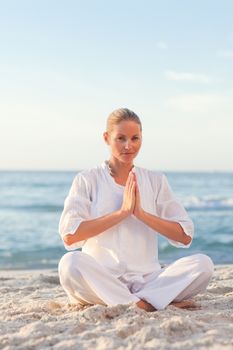 Peaceful woman practicing yoga on the beach against the sea