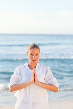 Active woman practicing yoga on the beach against the sea
