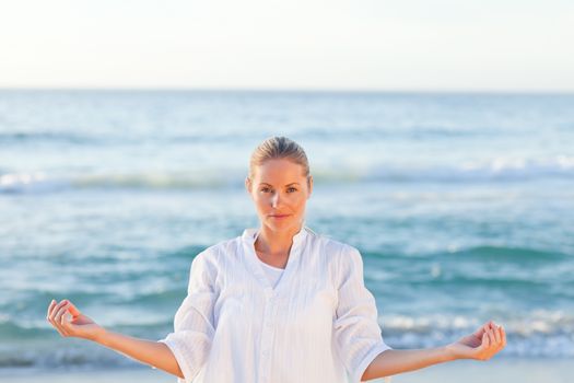 Active woman practicing yoga on the beach