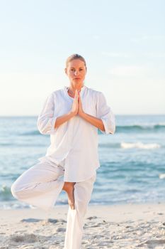 Active woman practicing yoga on the beach