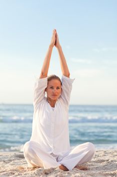 Active woman practicing yoga on the beach