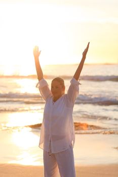 Woman practicing yoga during the sunset against the sea