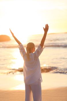 Woman practicing yoga during the sunset against the sea