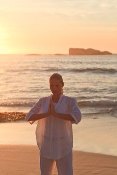 Woman practicing yoga during the sunset against the sea