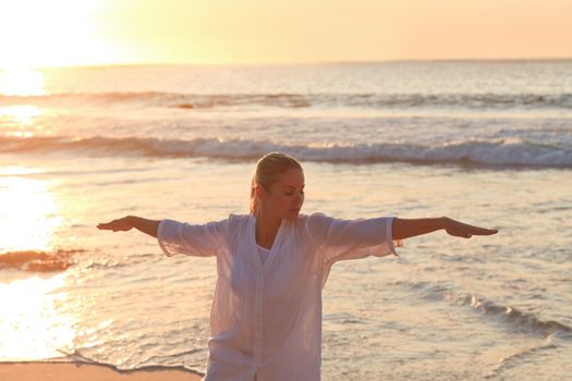 Woman practicing yoga during the sunset against the sea