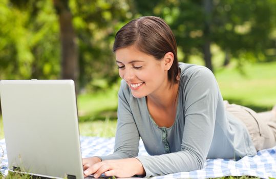 Woman working on her laptop in the park during the summer