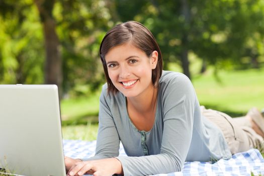 Woman working on her laptop in the park during the summer