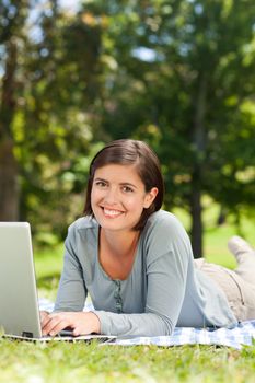 Woman working on her laptop in the park during the summer