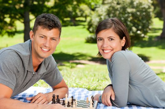 Couple playing chess in the park during the summer